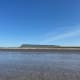 Seen from across the gently lapping waters, Ben Bulben, a massive flat-rock formation in Ireland under a clear blue sky.