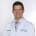 Dr. Brandon Rocque smiles broadly in a white lab coat.