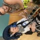 A man helps a younger man with cerebral palsy, who is seated in a wheelchair, while at the bowling ball return system.
