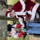 A smiling young man with cerebral palsy is seated in his wheelchair outside with cheerful Santa.