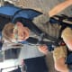 A smiling young boy with cerebral palsy, wearing glasses, sits in a stroller in an airport terminal.