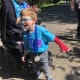 A young boy with CP, wearing glasses, blue t-shirt, jeans, and a red arm cast, proudly sports a medal as he walks on a road.
