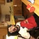 A smiling man with cerebral palsy is seated in a wheelchair at the kitchen island with the wooden craft project he built.