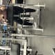 A masked woman with CP, wearing workout clothes, sits amongst fitness equipment in a gym while holding a hand weight.