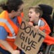 A young boy with CP in a wheelchair and a woman smile at each other. The boy is holding a sign that reads ‘Don’t Give Up’.