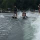 A man with CP enjoys adaptive water skiing on the rough grey waves created in a boat’s wake while accompanied by an instructor.