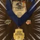 A rectangular gold medal with a blue ribbon from the NASTAR Regional Championships is displayed against a dark wood background.