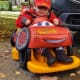A smiling little boy with CP sits in a Firefly Scooot wearing a red ‘Lightning McQueen’ car costume from the movie ‘Cars’.