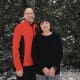 A smiling couple with cerebral palsy stand together against a snowy rock background.