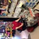 A smiling woman with CP, wearing a red t-shirt, rides a red mobility scooter down the paper goods aisle in the supermarket.