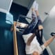 A woman with cerebral palsy lies on a home gym system using resistance bands to exercise her arms.