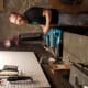 A smiling man with cerebral palsy stands at his garage workstation surrounded by different types of tools.