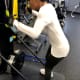 An adult with cerebral palsy concentrates on using a skiing machine at a gymnasium.