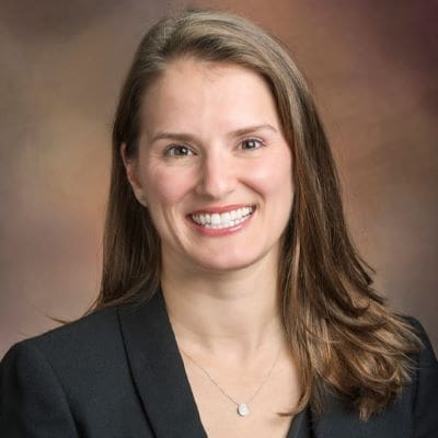 A woman with shoulder length brown hair smiling in a black blazer