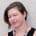 Dr. Sara Lewis, with short, asymmetric auburn hair and blue eyes wearing a black tank top.