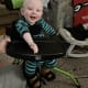 A boy with cerebral palsy in his stander wearing green and blue striped pajamas.