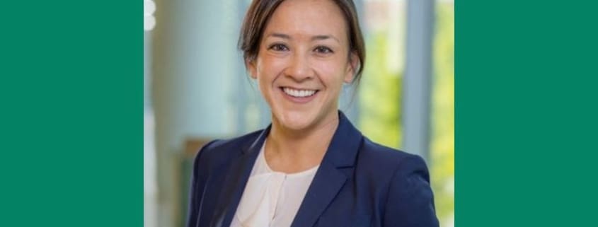 Dr. Sarmiento with brown hair pulled back in a navy blue blazer and a broad smile