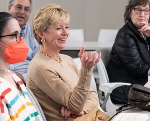 A woman with short blonde hair gesticulates while smiling in a family engagement in research breakout