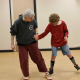 A boy with cerebral palsy holds hands while dancing with an instructor in an adaptive dance class