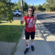 A young woman with genetic cerebral palsy wheres a bright red t-shirt walking down the sidewalk